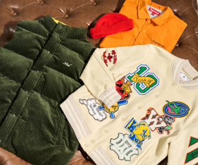 Clockwise from right, a beige Off-White appliqué varsity jacket, a green Kith Morris vest, an orange Supreme coach's jacket, and a red beanie sit on a brown leather tufted ottoman.