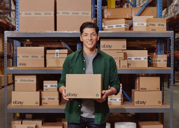 Bulk-listing tools click-through with image of a man in a green button-up holding an eBay box, standing in front of racks filled with eBay boxes in a warehouse.