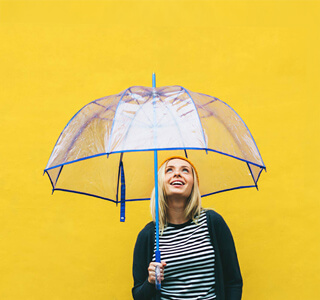 Frau mit blauem transparentem Regenschirm auf gelbem Grund