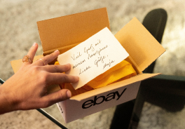 Ein Hand öffnet ein eBay-Paket mit einer handgeschriebenen Notiz.