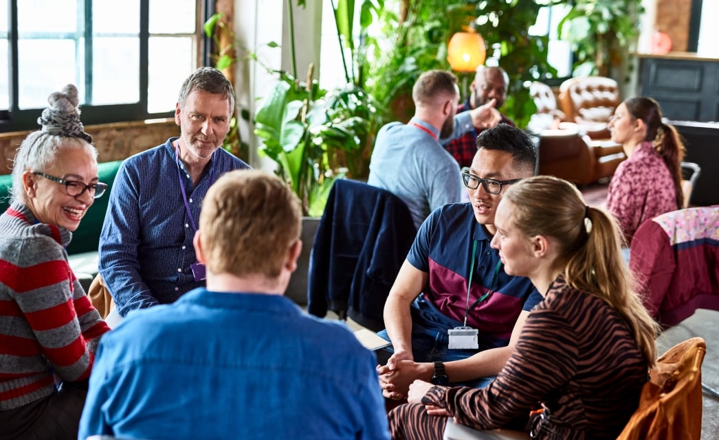 A group of adults sat in a circle having a conversation at a networking event