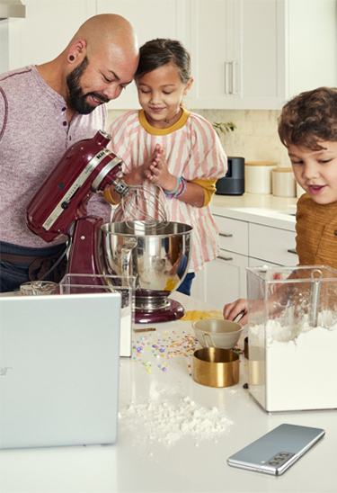 Family in the kitchenusing a stand mixer, a laptop and a smartphone