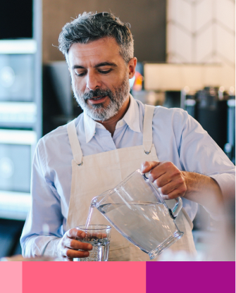 man with apron pouring water on glass