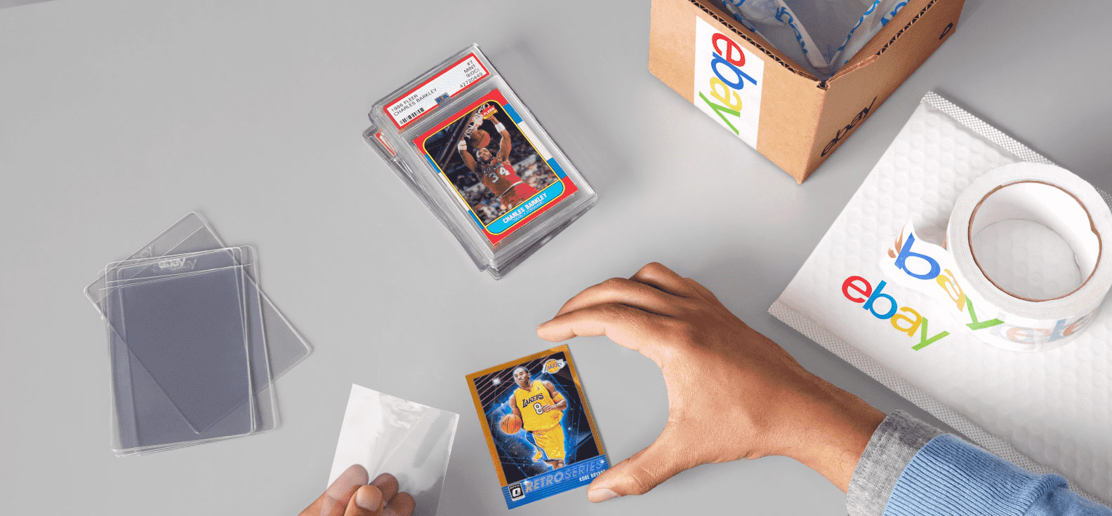 A person laminating sports cards on a light grey table. 