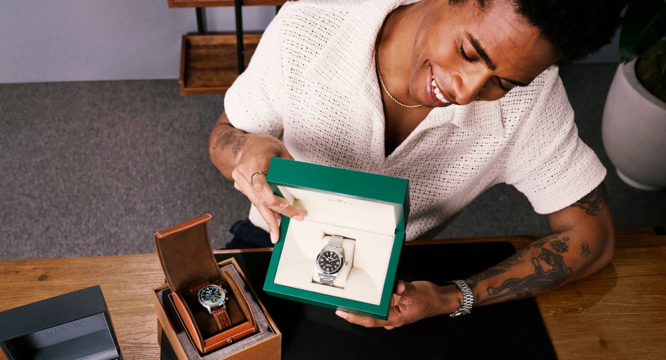 A man holding a box containing a watch linking to Authenticity Guarantee