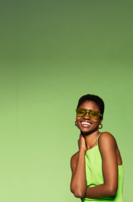 A black woman with light green dress and green sunglasses
