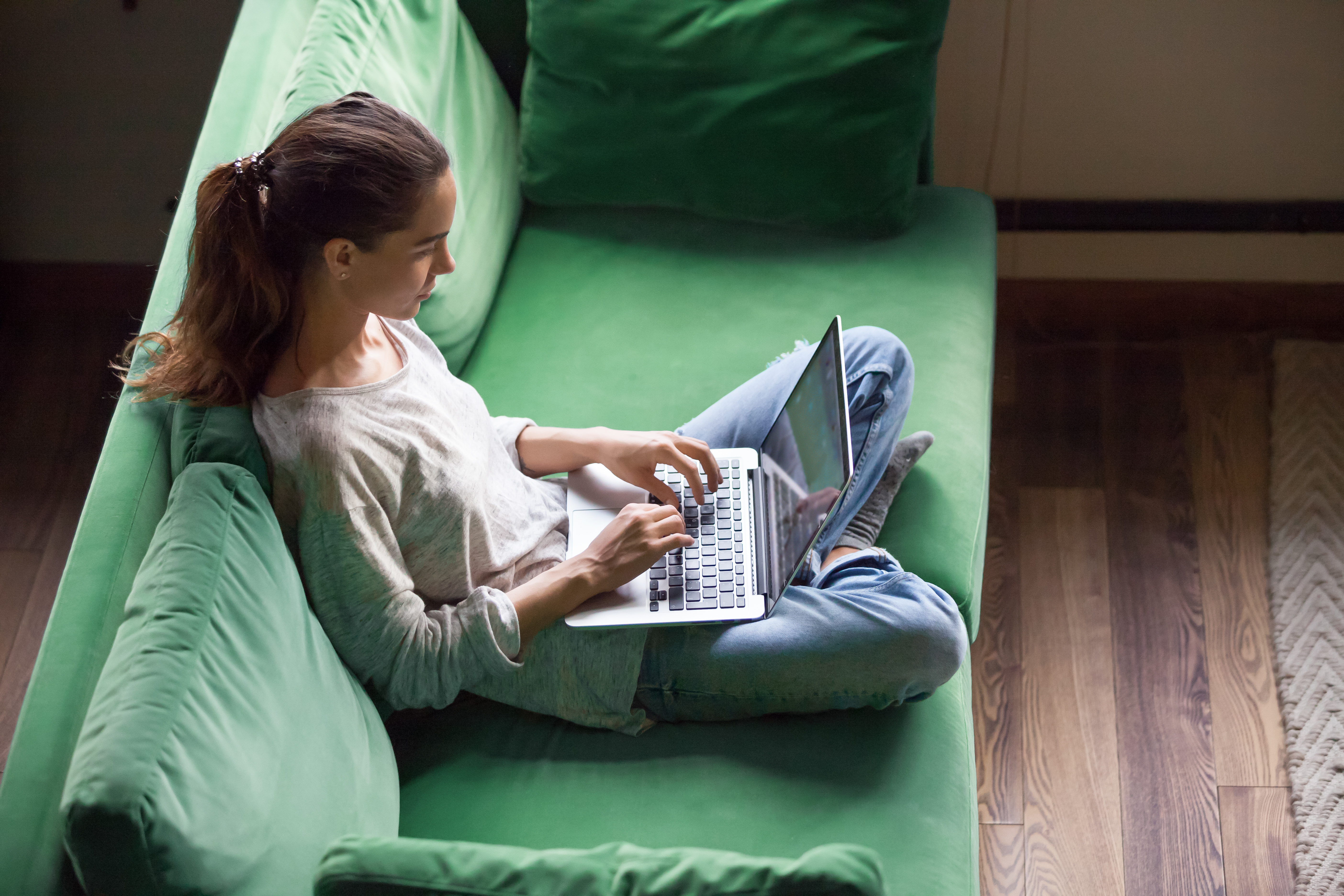 woman with laptop on green sofa