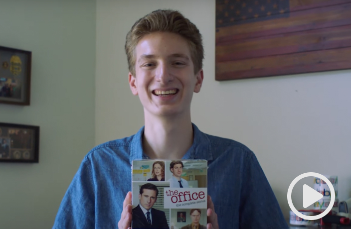 Video thumbnail of Jude Lugo smiling into the camera as he holds a DVD box set of “The Office” TV series.