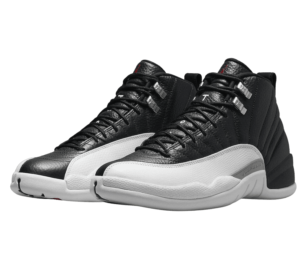 A pair of AJ12 sneakers in black leather, white mudguards, light gray soles, and metallic lace locks.