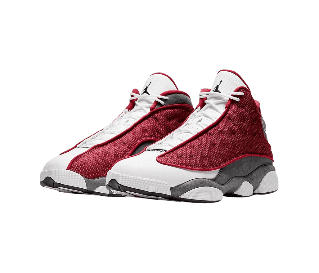 A pair of AJ13 “Red Flint” sneakers with white toeboxes, and dark gray suede quarters, and dark red fabric vamps with polka-dotted embroidery.