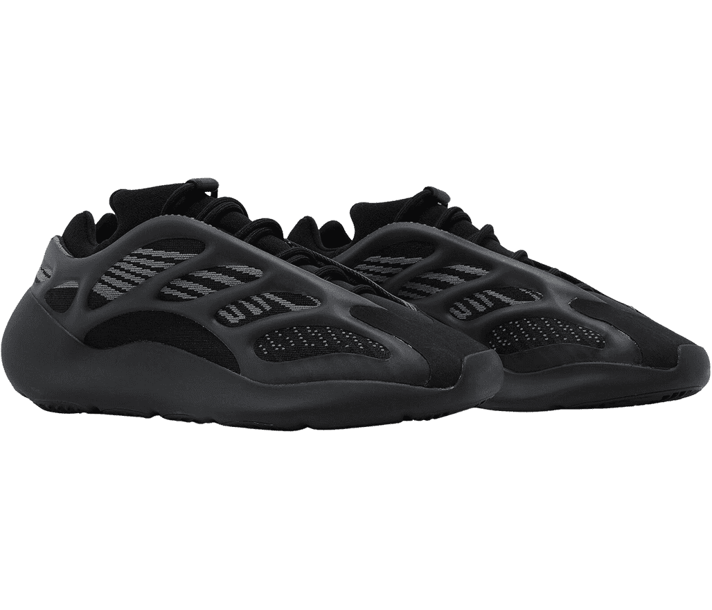 An all-black pair of Yeezy Boost 700 V3 “Dark Glow” sneakers with mesh uppers, suede toeboxes, and a rubber cage overlay.