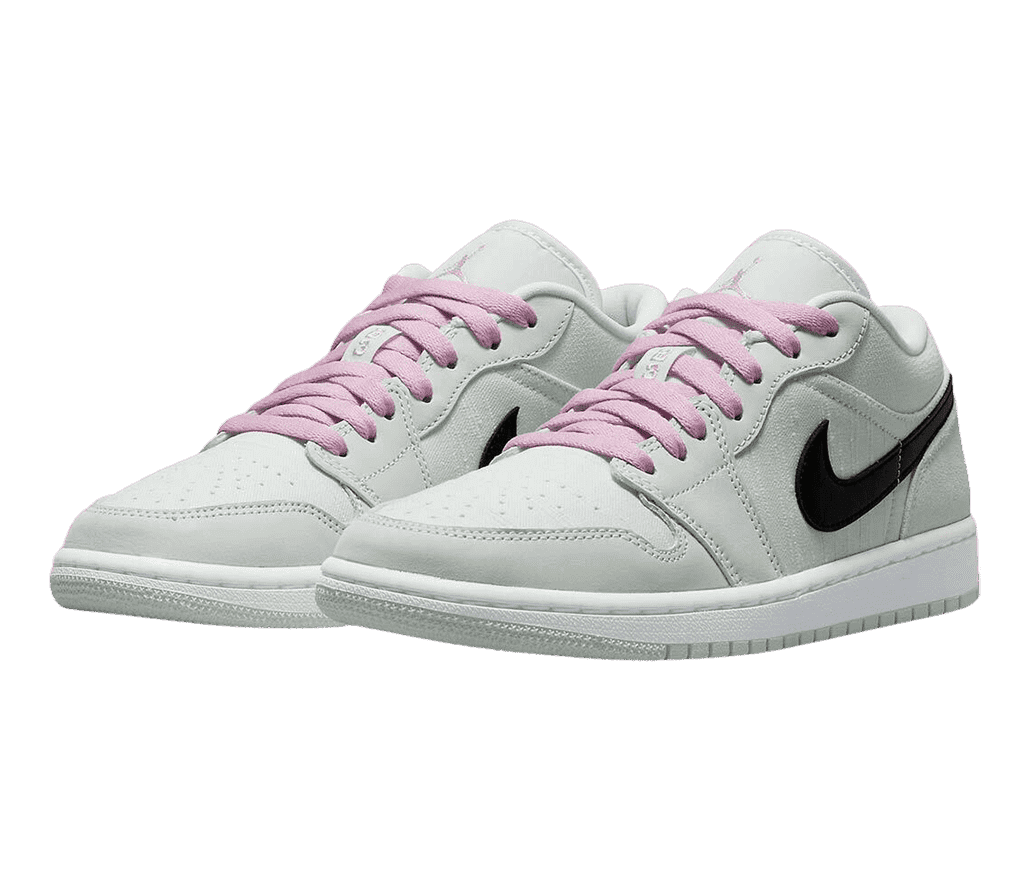 An off-white pair of AJ1 Low sneakers in canvas and suede with pink laces, white midsoles, and black Swooshes.