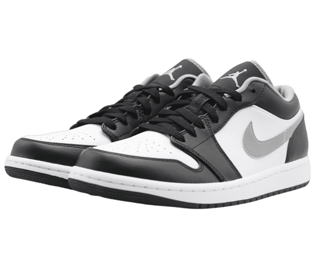 A black and white pair of AJ1 Low sneakers with silver lining, Jumpman logos on the tongues, and Swooshes.