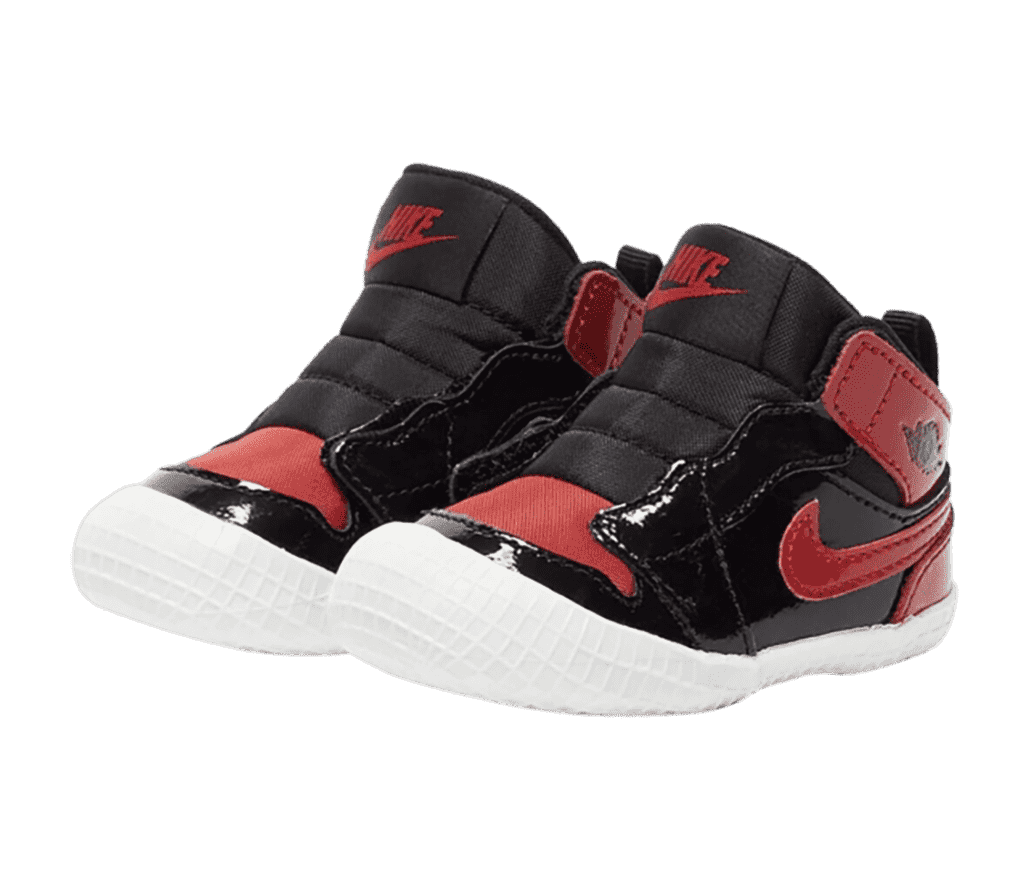 A pair of AJ1 Crib “Patent Bred” sneakers in black and red with white gridded soles wrapping over the toe.