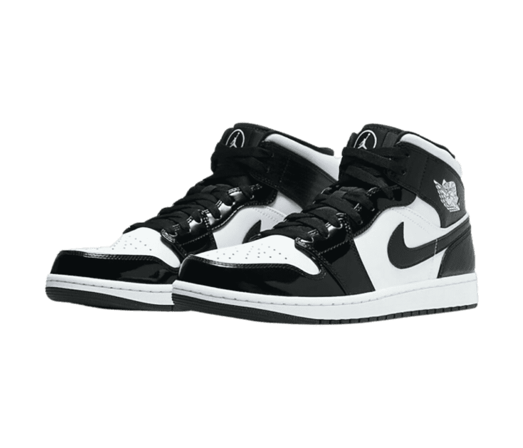 A pair of black and white AJ1 Mid sneakers with patent leather overlays and silver Jumpan logos encircled on the tongues.