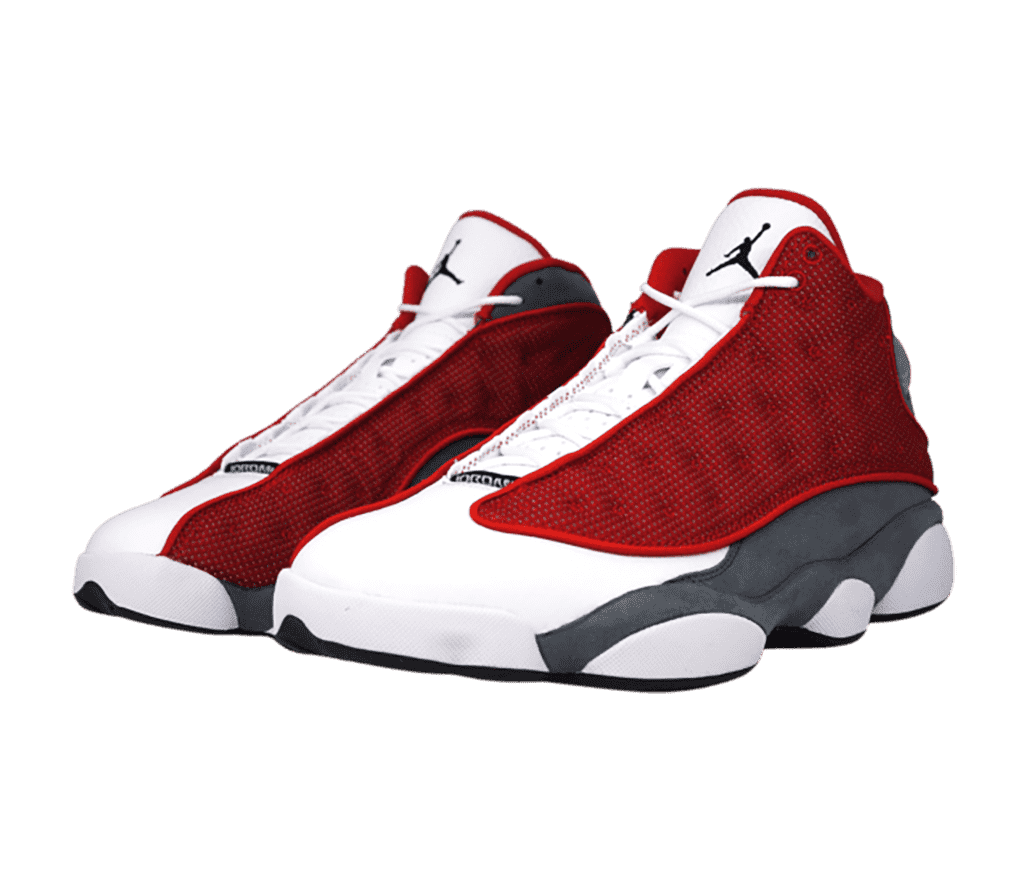 A white pair of AJ13 “Red Flint” sneakers with dark gray suede quarters, and red fabric vamps.