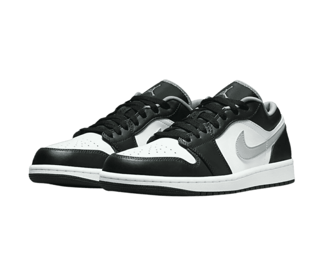 A black and white pair of AJ1 Low sneakers with silver lining, Jumpman logos on the tongues, and Swooshes.