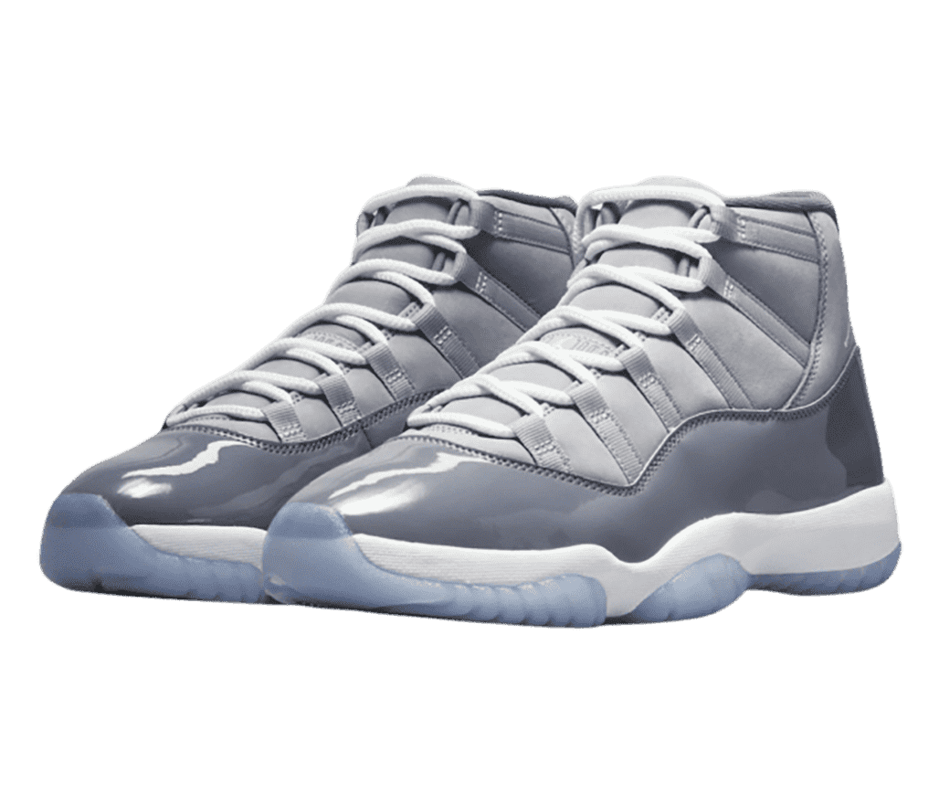 A pair of AJ11 sneakers in two shades of gray with patent leather mudguards and blue translucent outsoles.