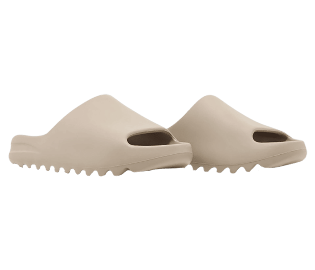 A pair of light beige Adidas Yeezy slides with zig-zagged soles.