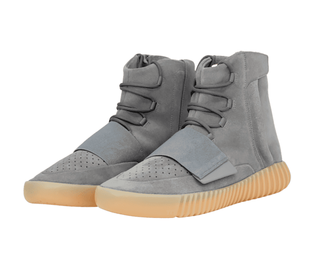 A pair of Yeezy Boost 750 sneakers in gray suede uppers, a thick rubber lace strap, and gum soles that are vertically ribbed.