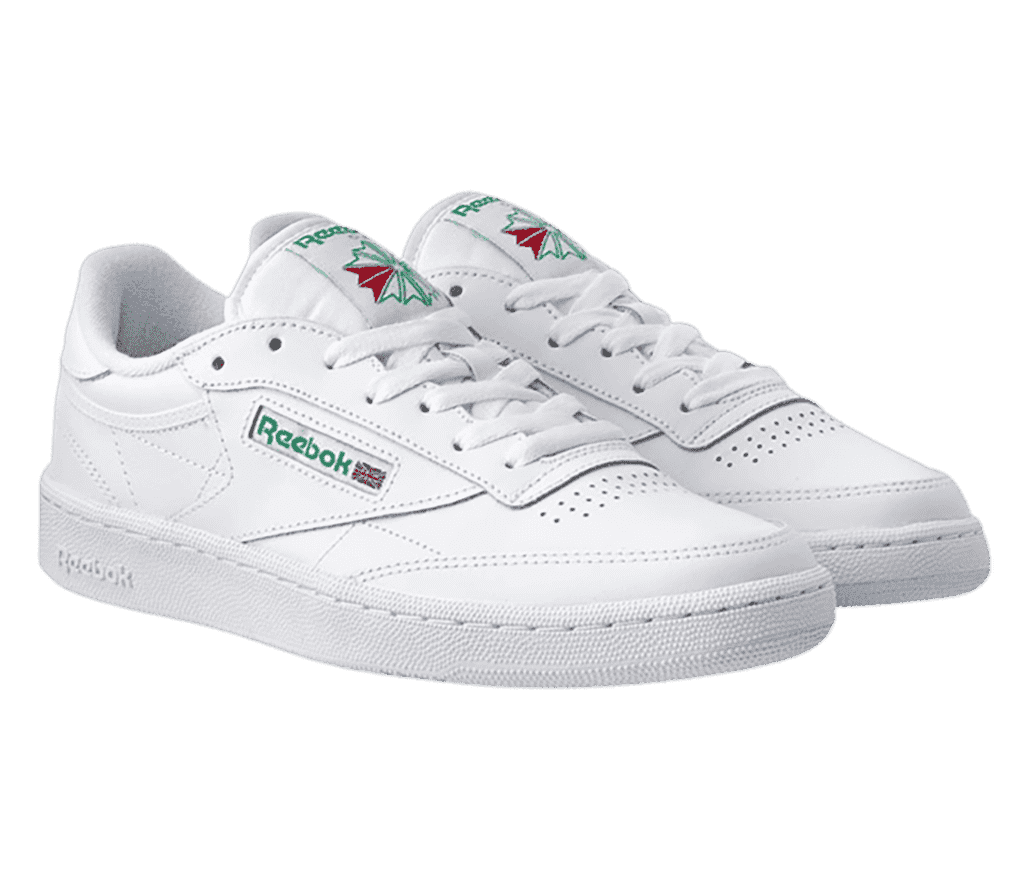 A pair of all-white Reebok shoes with the label stitched on a small tag in green.