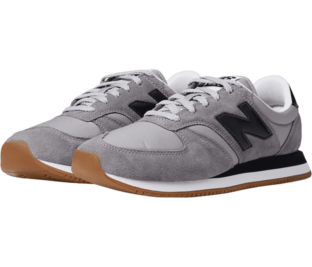 A pair of gray New Balance sneakers with a black logo and white, black, and brown along the sole.