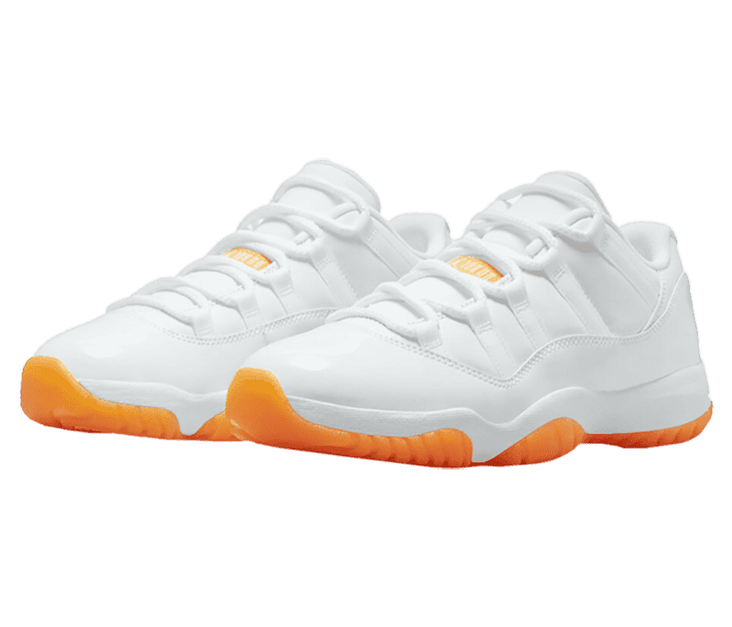 A white pair of AJ11 Low sneakers with patent leather overlays and bright orange outsoles.