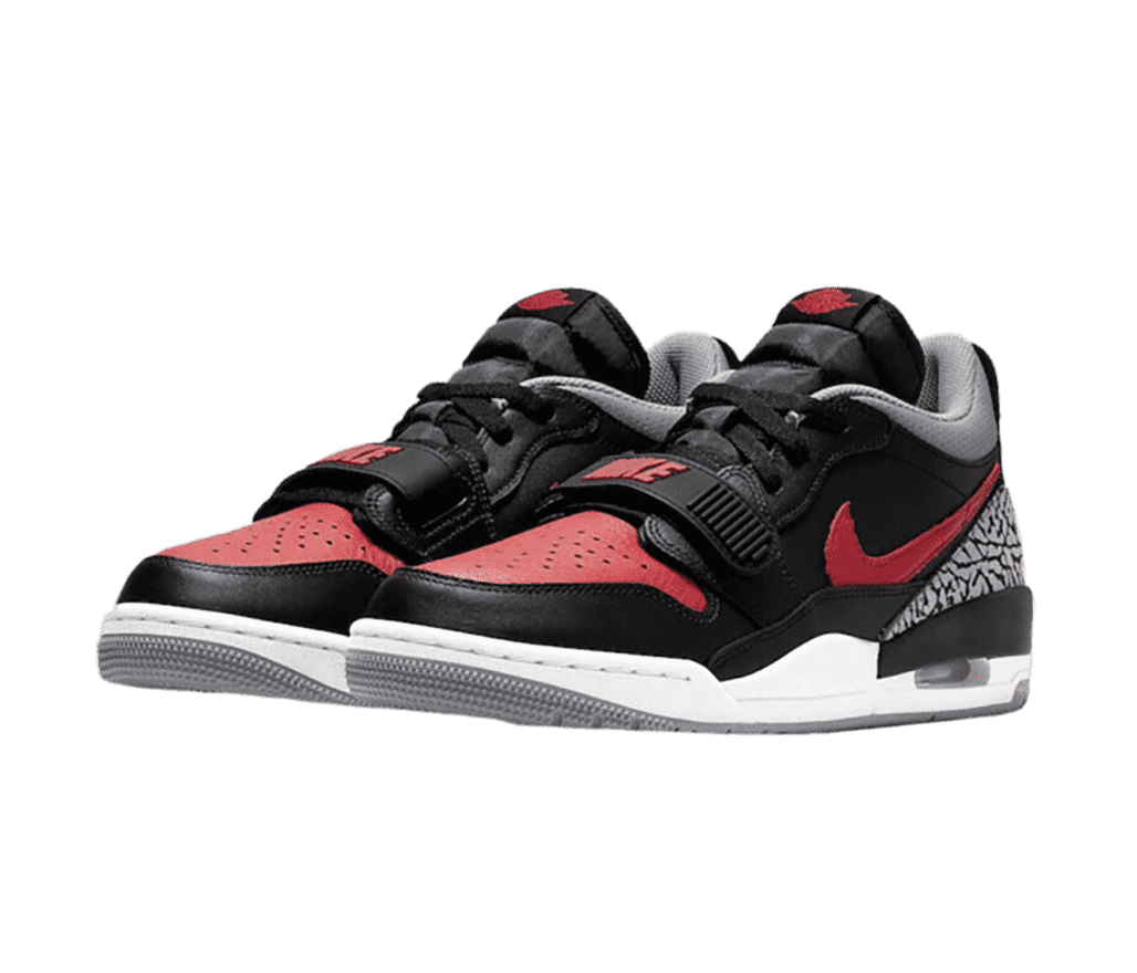 A pair of Jordan Legacy 312 Lows in black with red toeboxes and logos, gray elephant print heel counters, white midsoles, gray outsoles, and strap overlays above the over the laces.