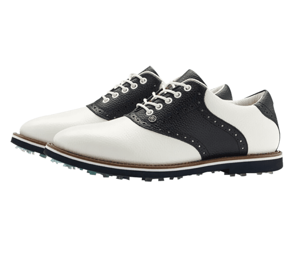 A pair of spiked GFORE Saddle Gallivanter golf shoes. They're dominantly white with a navy heel, outsole, and midsection.