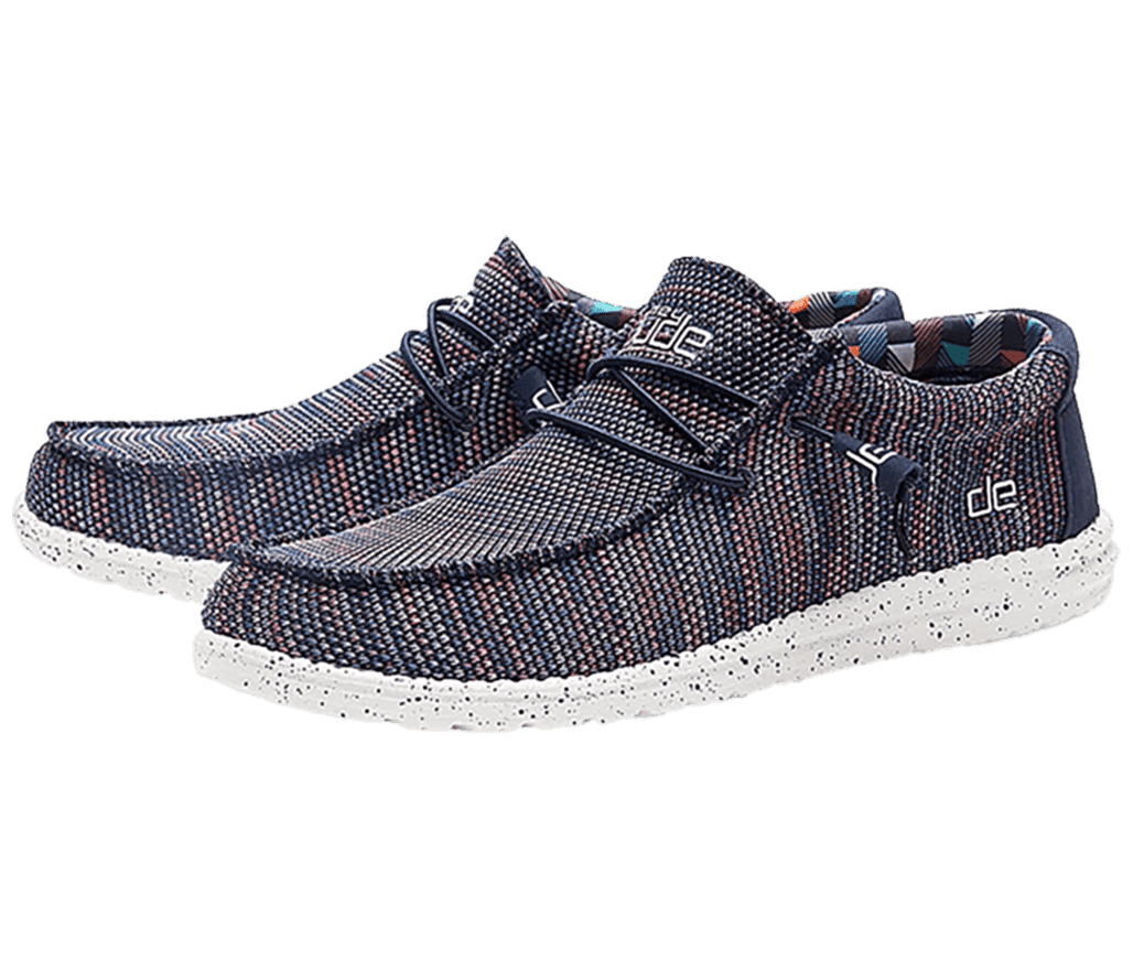 A pair of Hey Dude Wally Sox loafers in a blue and orange knitted texture, a textile patterned lining, and a white sole speckled with black.