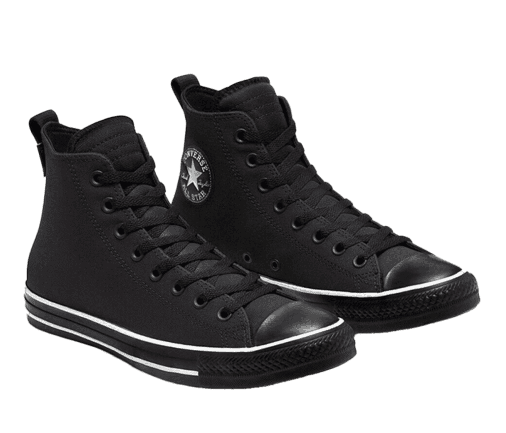 A pair of all-black Converse All Star shoes. The soles of the shoe feature a thin white horizonal line that stretches along the entire shoe.