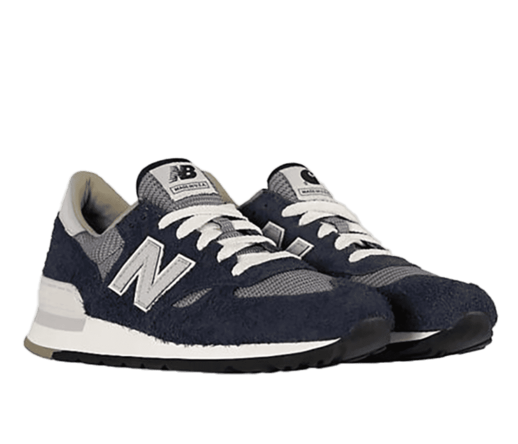 A pair of navy blue New Balance sneakers with gray and white accents on the bottom and top. The blue parts of the shoe have a slightly fuzzy texture to them.