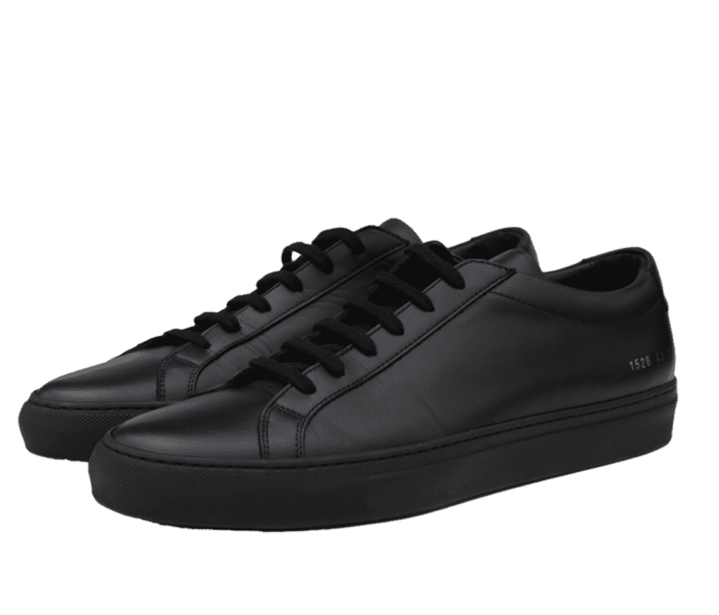 A pair of all-black Common Projects sneakers. In the back heel, the number 1528 is written in a small gold font.