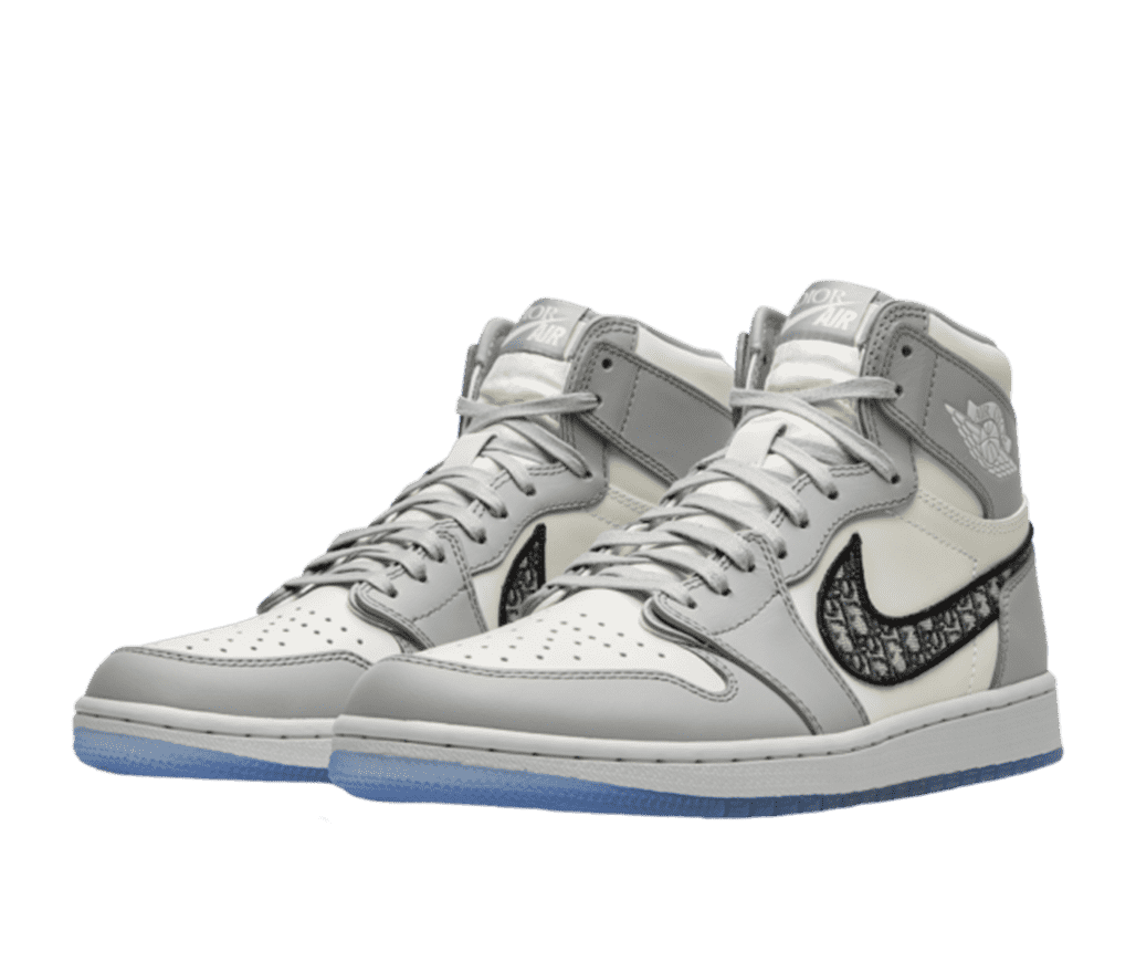 A pair of white and silver Dior Air Jordan sneakers. The white sole of the sneaker features a light blue accent on the lower half. The Nike logo is filled in with Dior's logo in a repeating pattern.