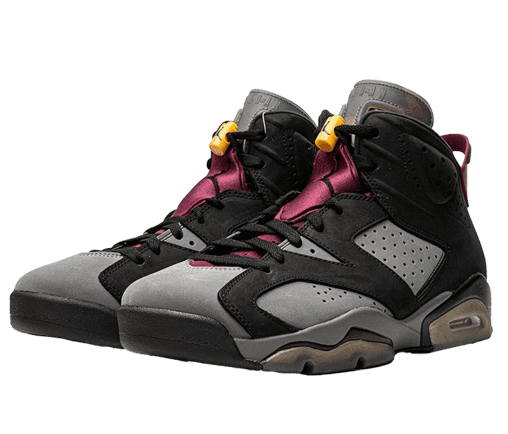 Front right-angled view of a pair of Air Jordan 6s. The shoe has gray nubuck upper base with black overlays on the rest of the panels. There are zig-zag accents of black, bordeaux, yellow, blue, and green on the tongue and a wine-like bordeaux Jumpman logo on the lateral sides.