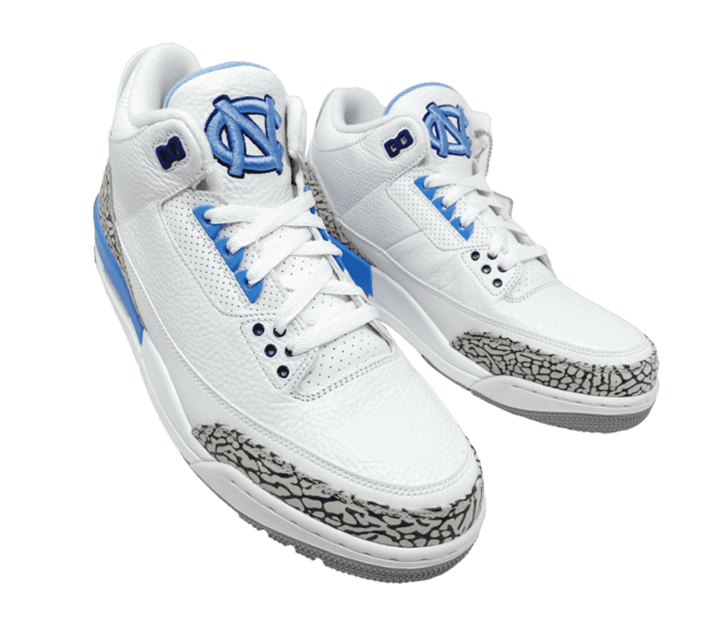 A top-angled, fish eye shot of the Air Jordan 3 'UNC'. The shoe is dominantly white with a gray outsole and a black-and-gray elephant print on the tip and foxing. The back portion of the midsole is a light blue, matching with the upper eyelets, tongue lining, and the UNC logotype on the tongue.