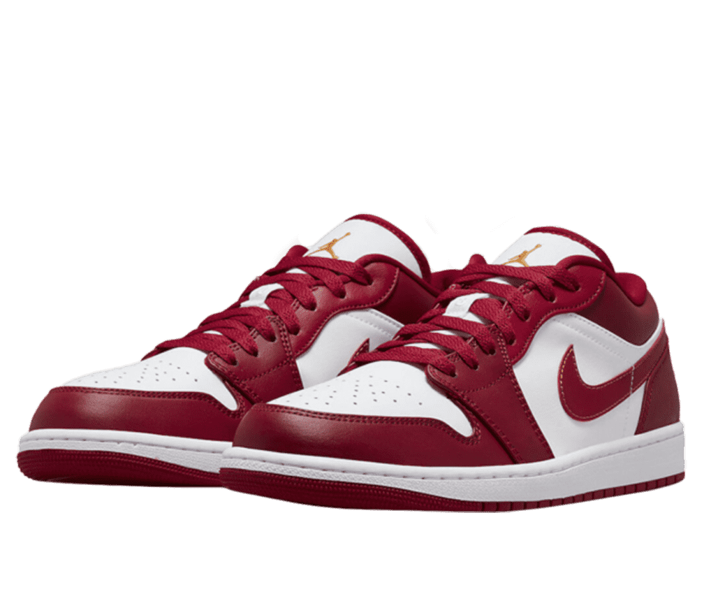 A front left-angled view of a pair of low top Air Jordan 1s. The base of the shoe, including the top of the toe, side, and tongue are white. The shoes feature a red overlay, red laces, and red Nike swoosh on the side. On the tongue, is a gold Air Jordan logo.