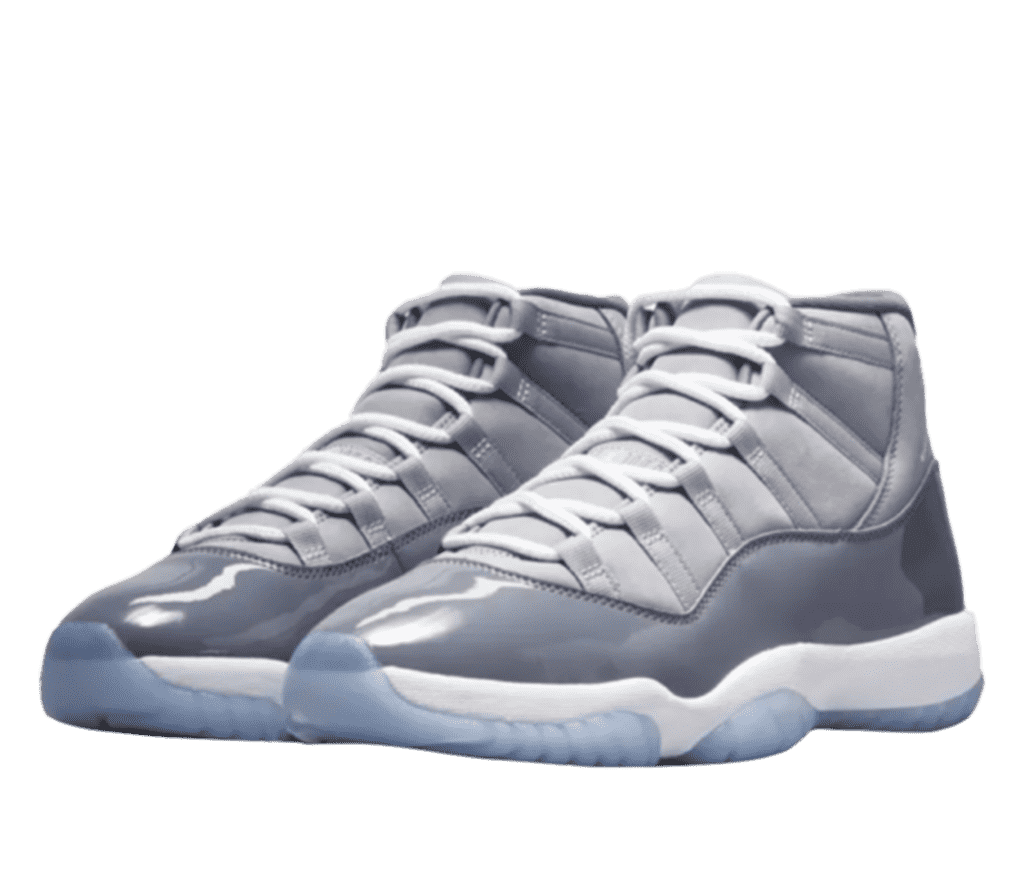Front left-angled view of a pair of light grey Air Jordan 11s. The sole is powder blue. The bottom half of the shoe is shiny patent leather panel in darker shade of grey. The top is a lighter-grey fabric.