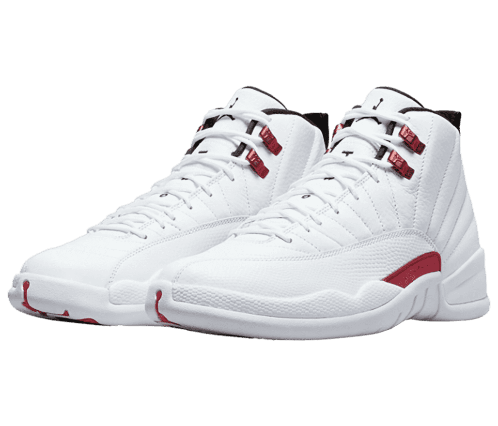 An all-white pair of AJ12 Retro sneakers in leather mudguards, red accents on the lateral side, and red lace locks.