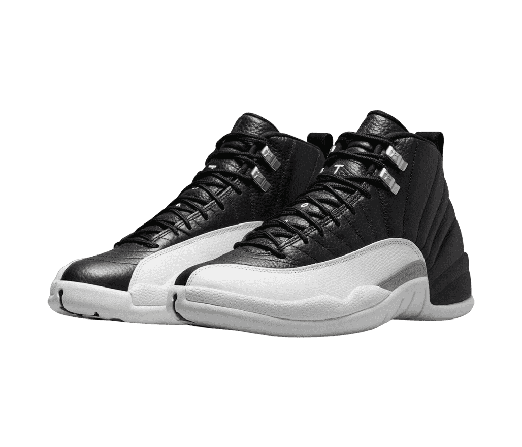 A pair of AJ12 sneakers in black leather, white mudguards, light gray soles, and metallic lace locks.