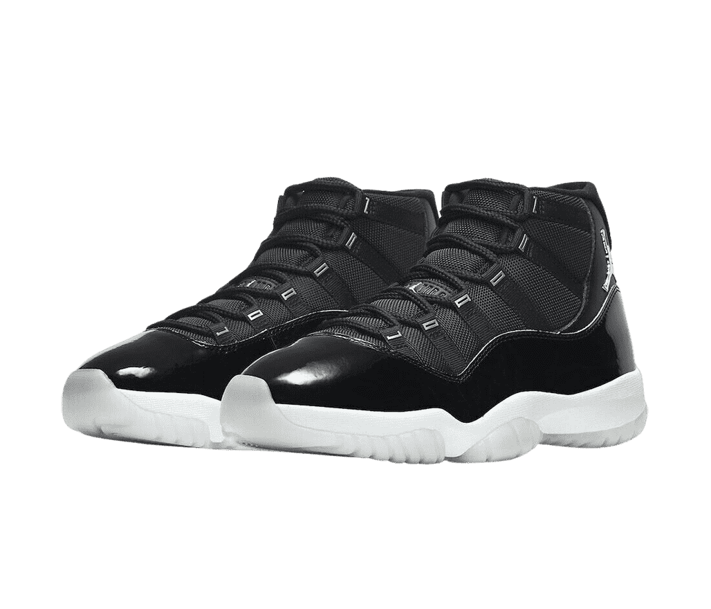 A black pair of AJ11 sneakers in leather and canvas, white midsoles, chrome Jordan logos under the collar, and light gray translucent outsoles.