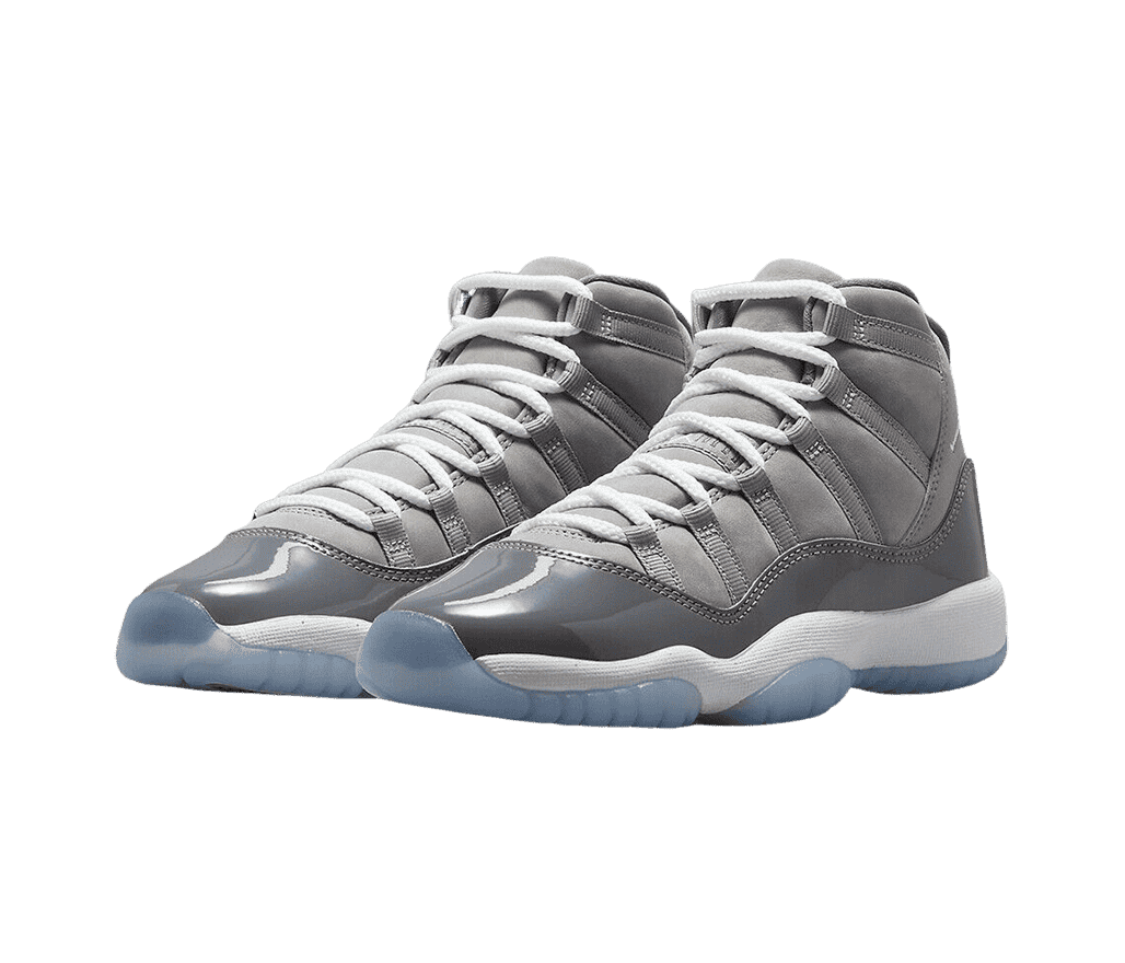 A patent leather and suede pair of AJ11 “Cool Grey” sneakers in two shades of gray uppers, white laces and midsoles, and blue translucent outsoles.