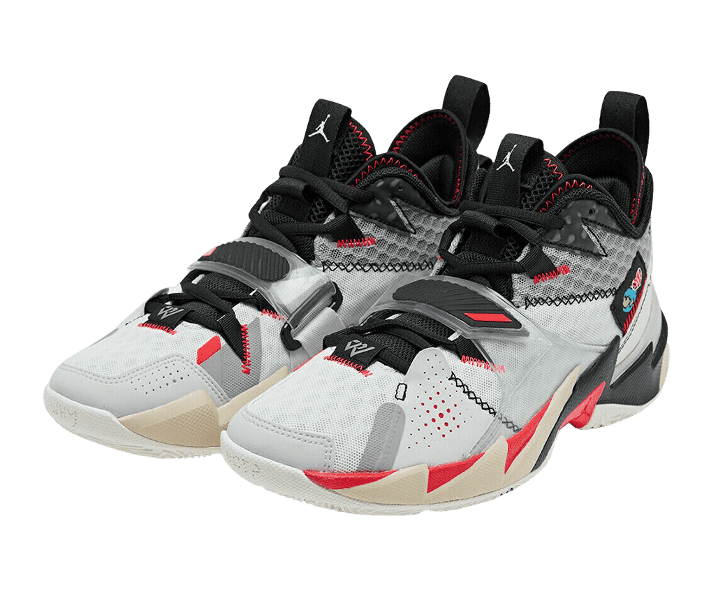 A pair of Jordan “Why Not” sneakers in the white bright and crimson black colorway. The shoes have orange, tan, gray, and black overlays and clear velcro ace straps.