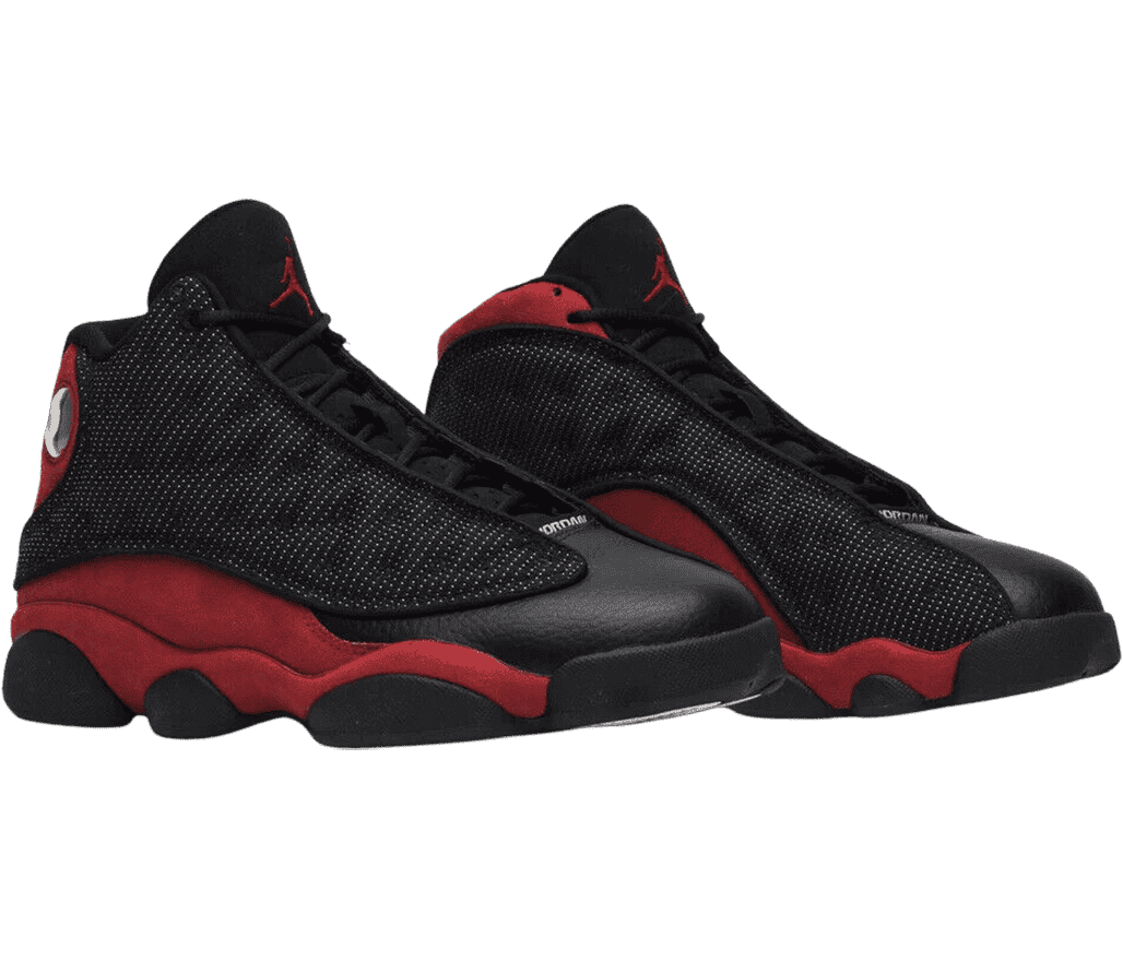A black pair of AJ13 “Bred 2017” sneakers with red suede quarters, black leather toeboxes and outsoles, and white-dotted fabric vamps with circular embroidery.