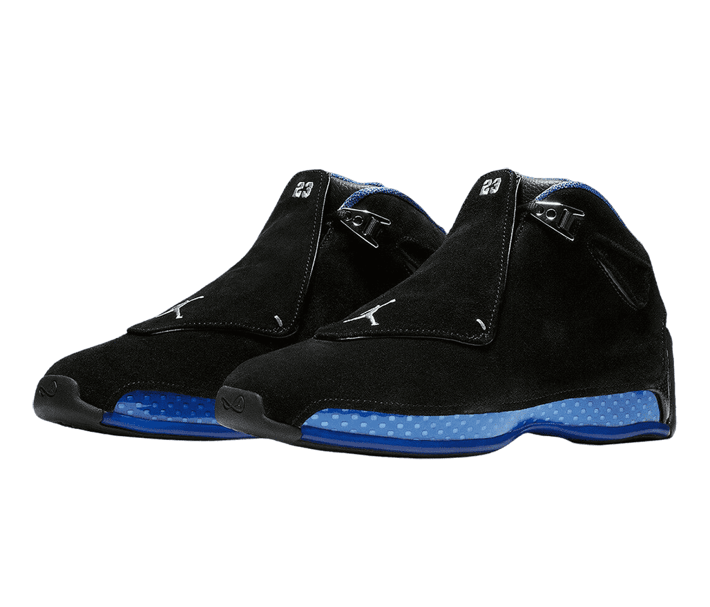 A black suede pair of AJ18 “Sport Royal” sneakers with polka-dotted blue semi-translucent midsoles, chrome lace locks, and lace covers with the number “23” and the Jumpman logo stitched on them in a silver gray.