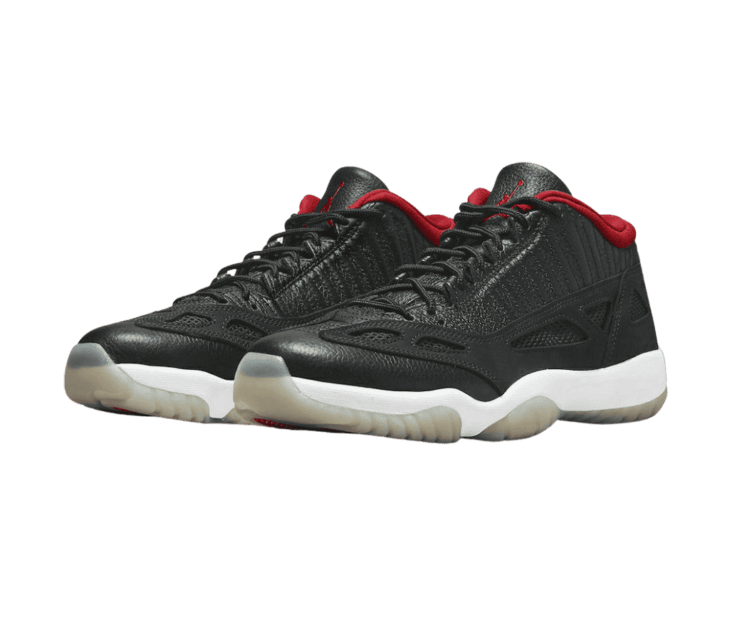 A pair of AJ11 Retro Low IE sneakers with leather uppers, a suede overlay, white midsoles, translucent off-white outsoles, and red fleece lining.