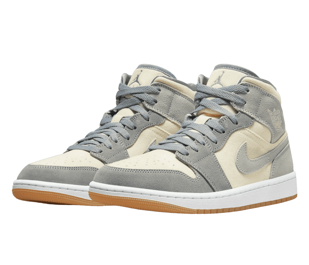 A suede pair of AJ1 Mid “Coconut Milk” sneakers with cream uppers, gray overlays, white midsoles, and gum outsoles.