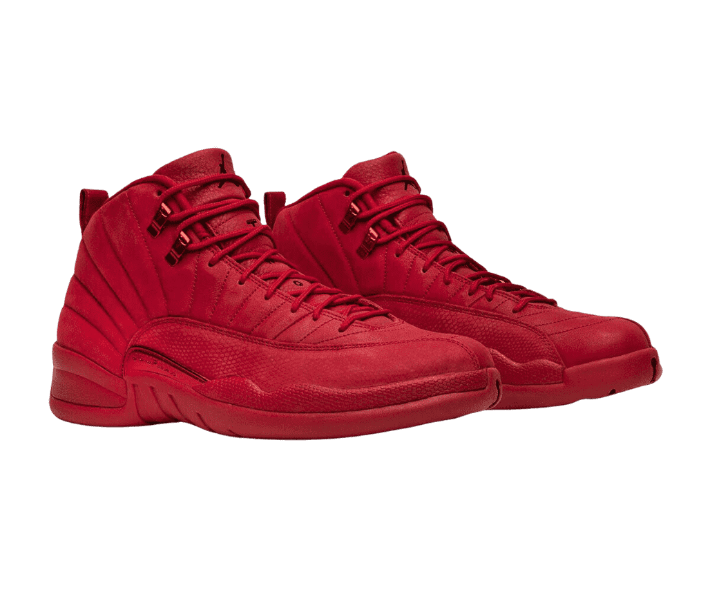 A red suede pair of AJ12 sneakers with leather tongues, rubber soles, and red metallic lace locks.