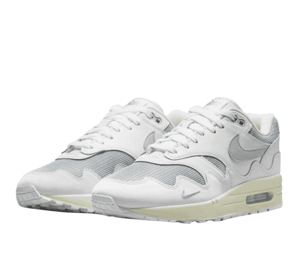 A pair of white and gray Nike Air Max 1s. The shoe features a wave-like pattern that stretches across the shoe. Near the front of the shoe is a small white Nike logo. On the side of the shoe, close to the back, is a larger white Nike logo.