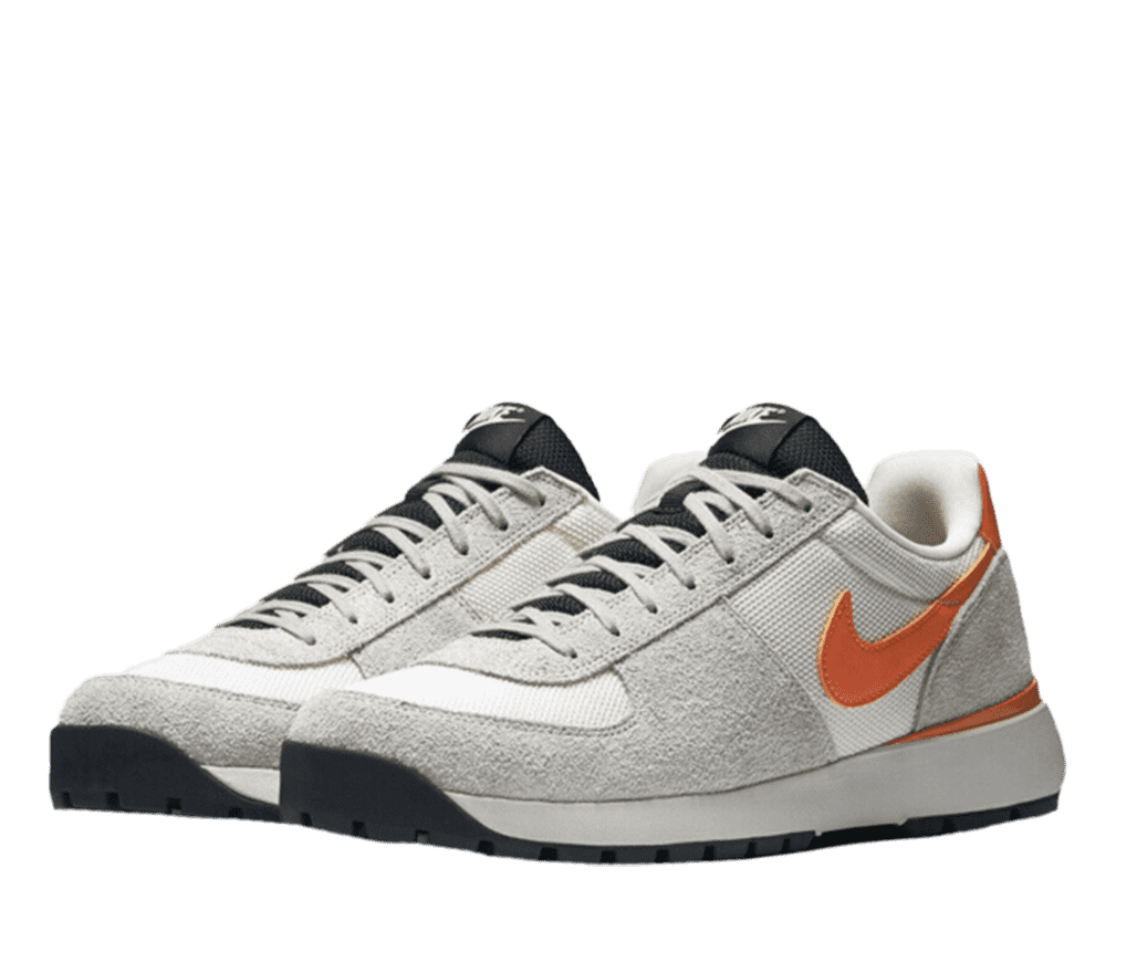 A pair of white and gray Nike sneakers. The Nike logo on the side of the shoe is orange, and the tongue is black.